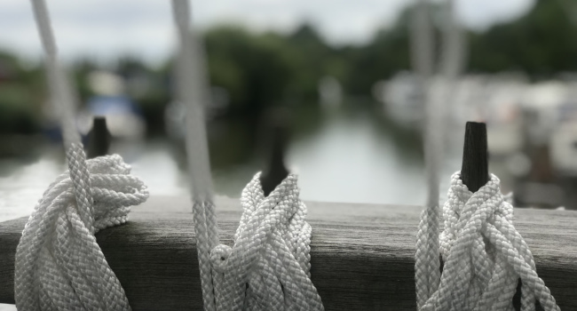 drei aufgewickelte Leinen, im Hintergrund Boote