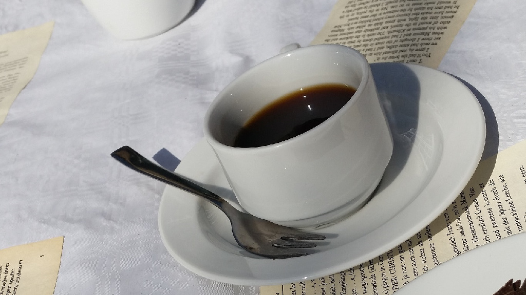 Kaffeetasse und Seiten mit gedrucktem
Text auf einer Tischdecke